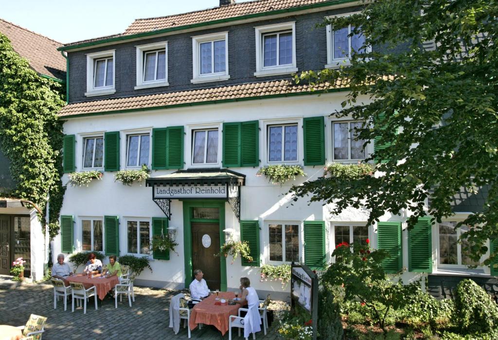 people sitting at tables in front of a building at Hotel Reinhold in Gummersbach