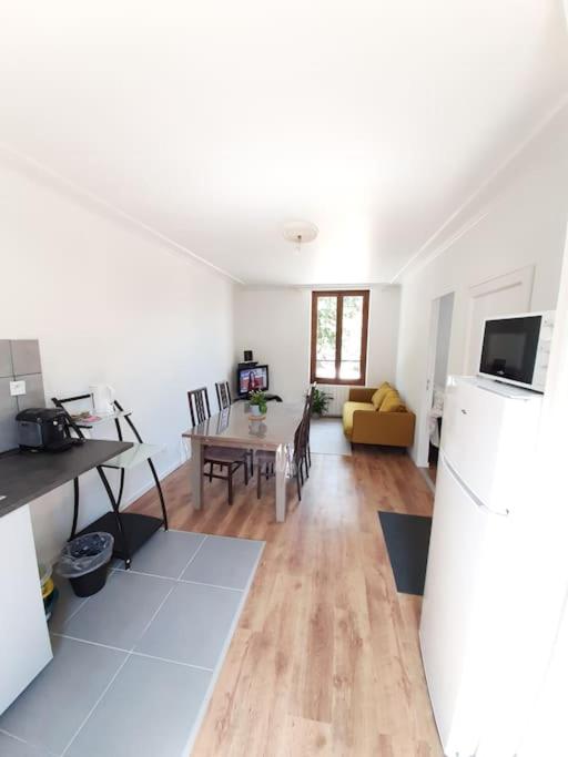 a living room with a table and a refrigerator at Résidence du Houx - 4 (Astérix, Aéroport CDG, Chantilly, Parc expos...) in Survilliers