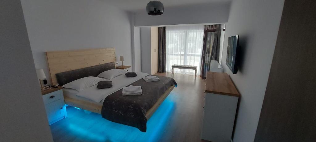 HAPPY SUMMER -Predeal في بريدال: غرفة نوم بسرير كبير عليها انارة زرقاء