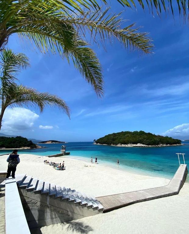 a beach with a palm tree and people on it at ABEDINI Boutique Hotel Ksamil in Ksamil
