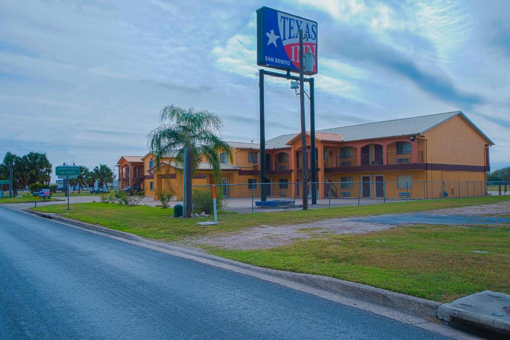 una carretera vacía delante de un hotel con un cartel en Texas Inn San Benito near Harlingen, en San Benito