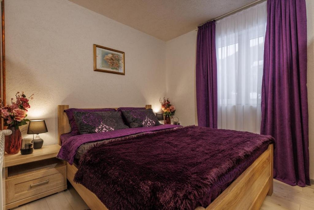 ein Schlafzimmer mit einem Bett mit violetter Bettwäsche und einem Fenster in der Unterkunft Family SPA Apartments Sunny&Shiny in Šavnik