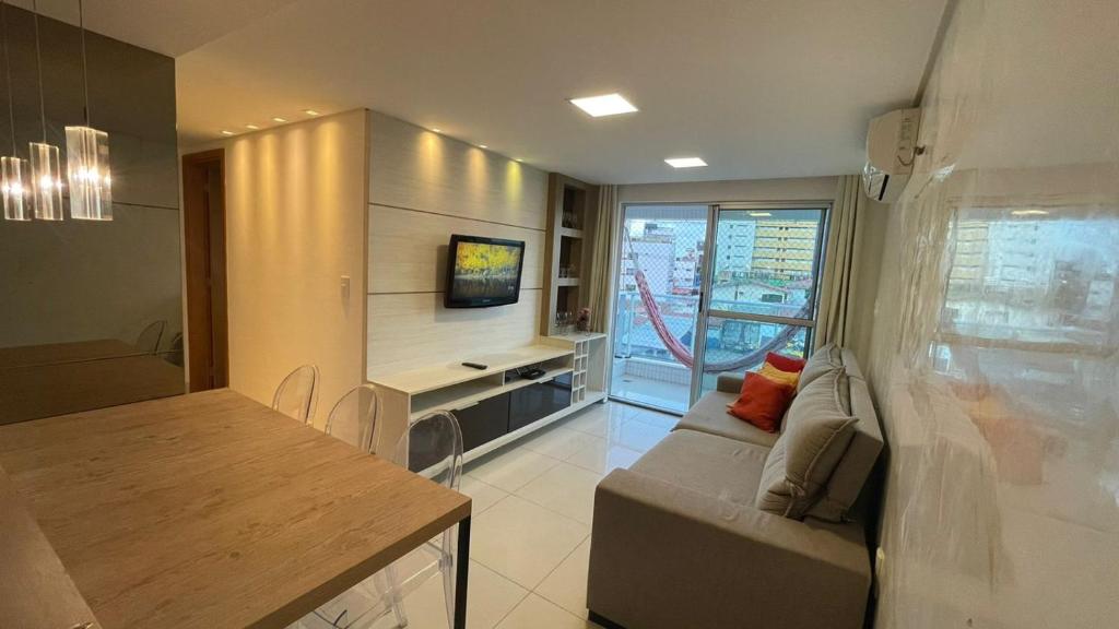 sala de estar con sofá, mesa y TV en Lindo Apartamento p/ 4 pessoas, a 60 m do mar, en João Pessoa