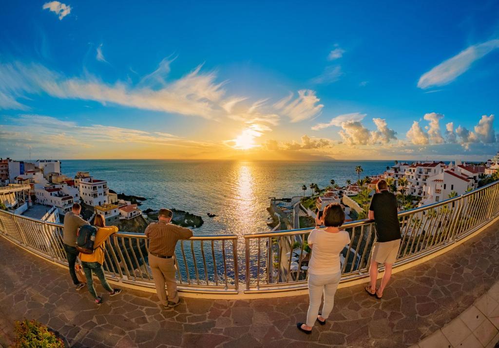 a group of people standing on a balcony looking at the sunset at La Mar 2 bed 2 bath in sought after position FREE WIFI in Puerto de Santiago