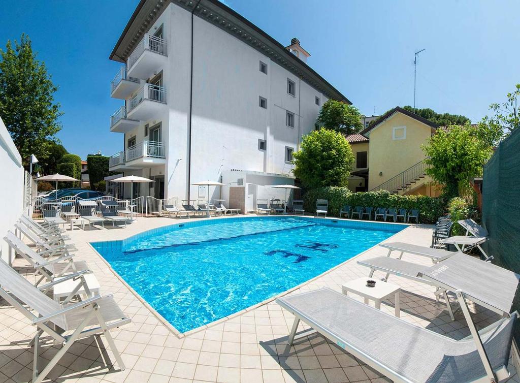 a swimming pool with chairs and a building at Hotel Embassy in Riccione