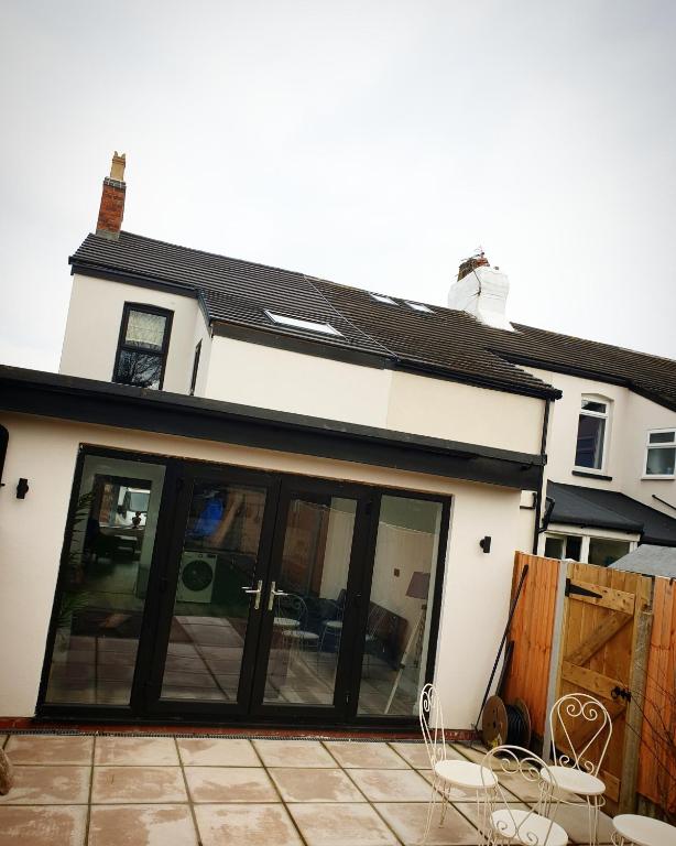 a house with large sliding glass doors on a patio at Dora Cottage in Formby