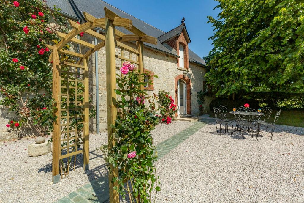 a garden with a wooden pergola and a table with roses at manoir de vauville in Fresville