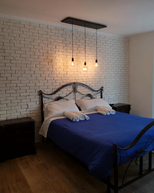 a bedroom with a bed with blue sheets and a brick wall at PortaLecce B&B in Brindisi