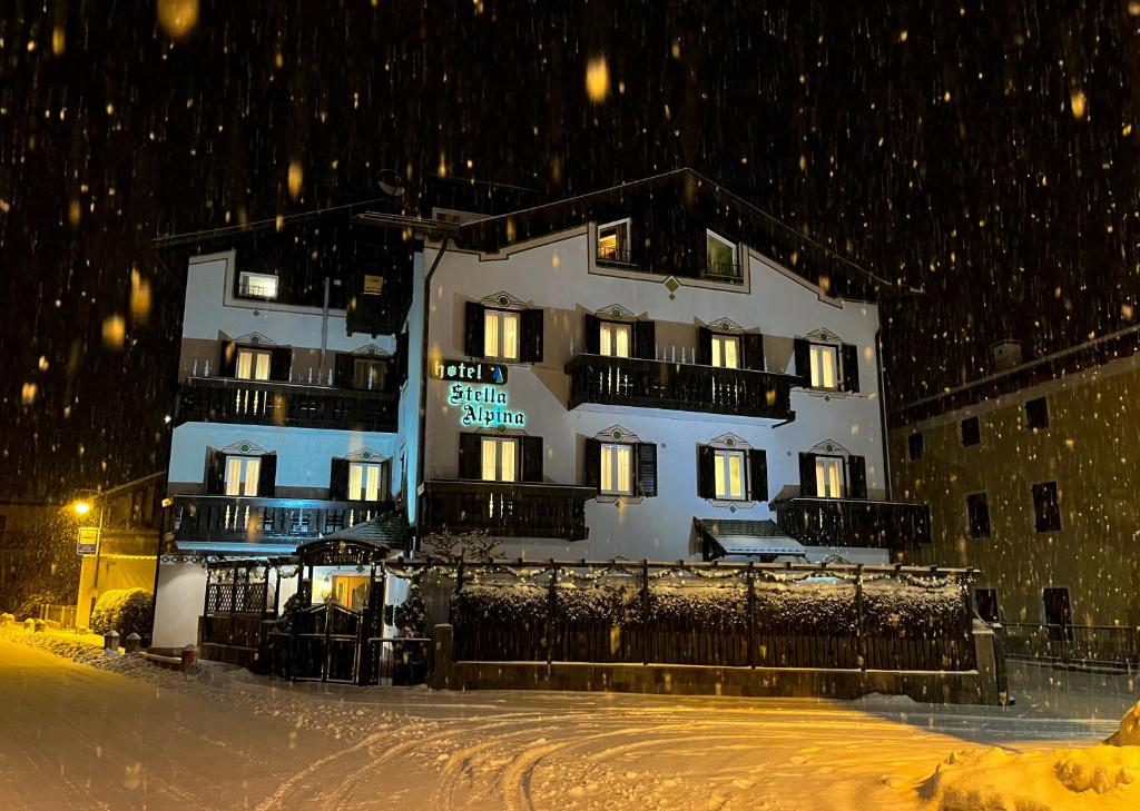 un grand bâtiment dans la neige devant dans l'établissement Hotel Stella Alpina, à Fai della Paganella