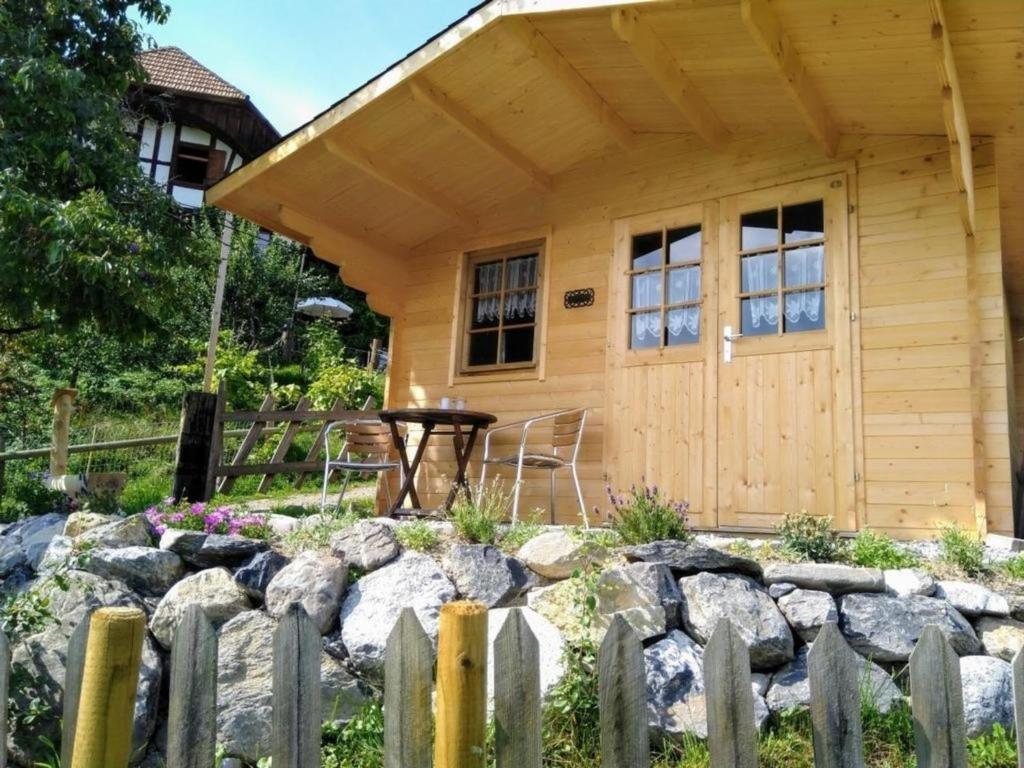 uma cabana de madeira com uma cerca em frente em Gartenhaus Zimmer em Rüeggisberg