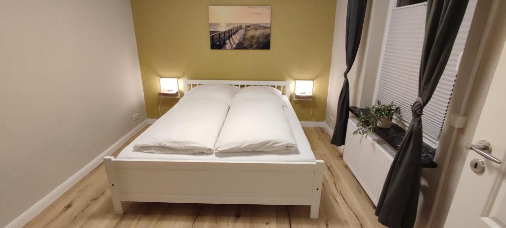 małe łóżko w małym pokoju z dwoma światłami w obiekcie Nordseezimmer - WLAN, Parkplatz, eigenes Bad, Fahrradschuppen, elektrischer Rollladen w mieście Otterndorf