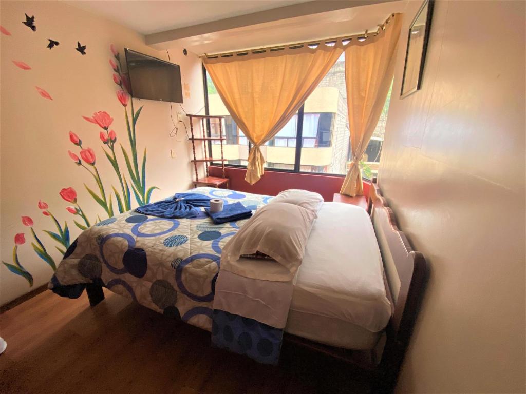 a bedroom with a bed in a room with a window at Hostal los Andes in Baños