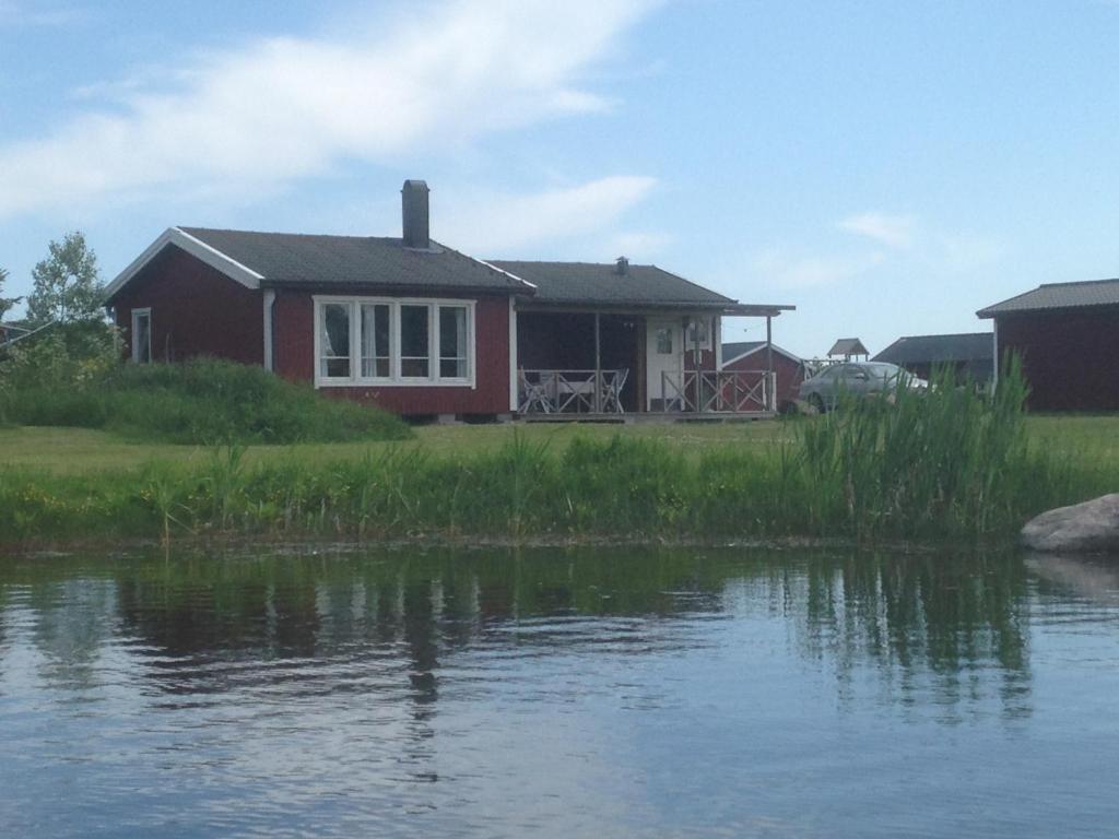 ein Haus neben einem Wasserkörper in der Unterkunft Svalsjöns Stugor Öland in Köpingsvik