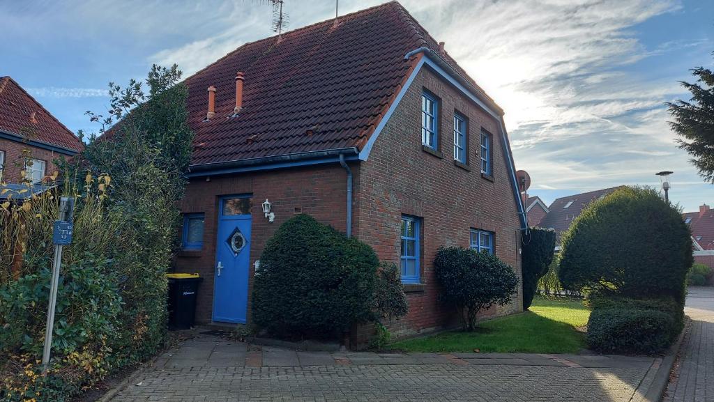 a brick house with a blue door on a street at Haus Nika in Carolinensiel in Carolinensiel