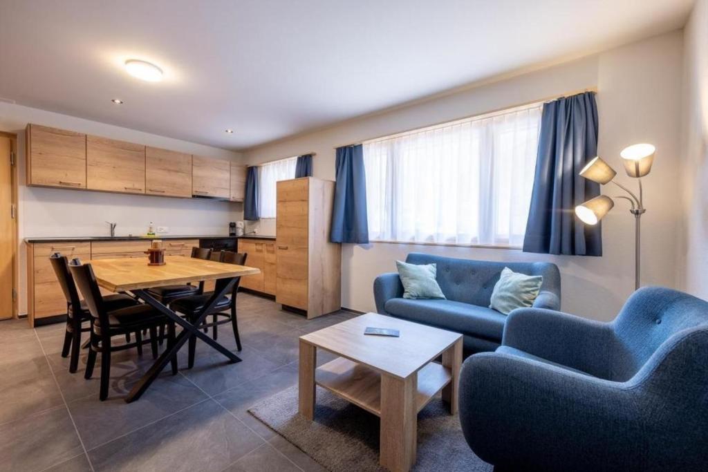 Apartment Edelweiss في Gadmen: غرفة معيشة مع أريكة زرقاء وطاولة