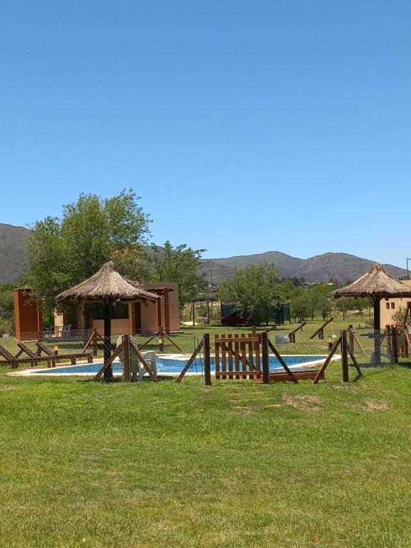 una piscina con una valla y un edificio con montañas en el fondo en Roena Cabañas en Villa Giardino