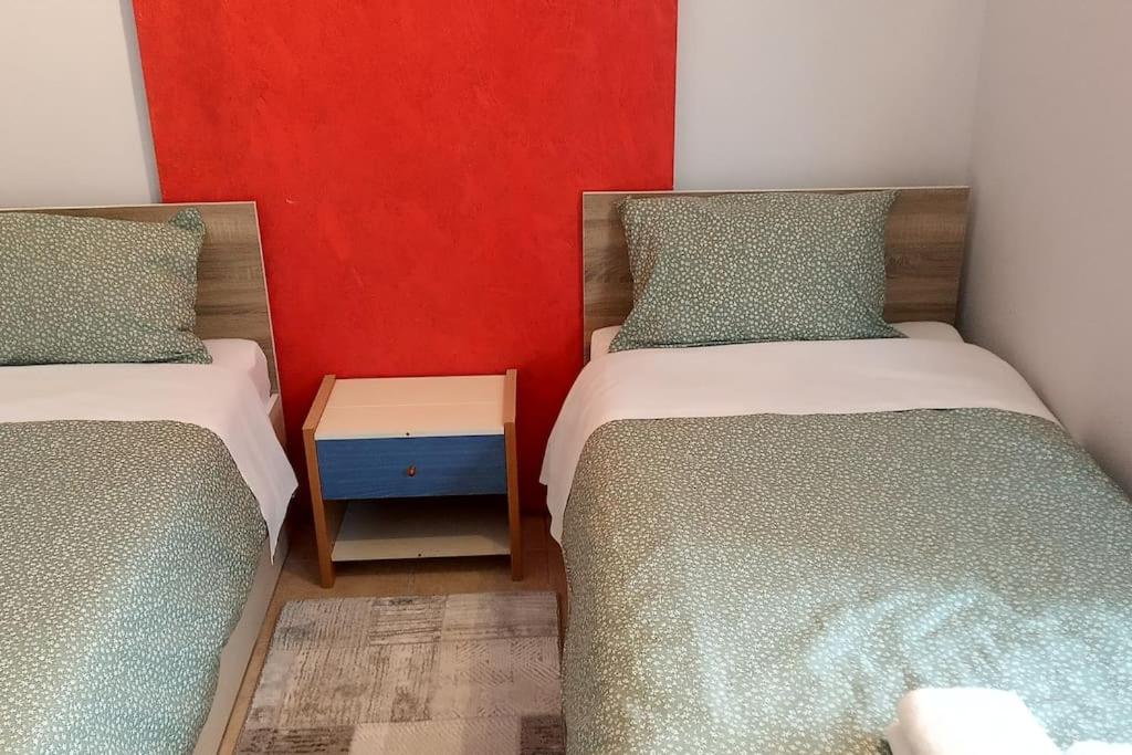 2 camas individuais num quarto com uma parede vermelha em Paris house 4 em Patra