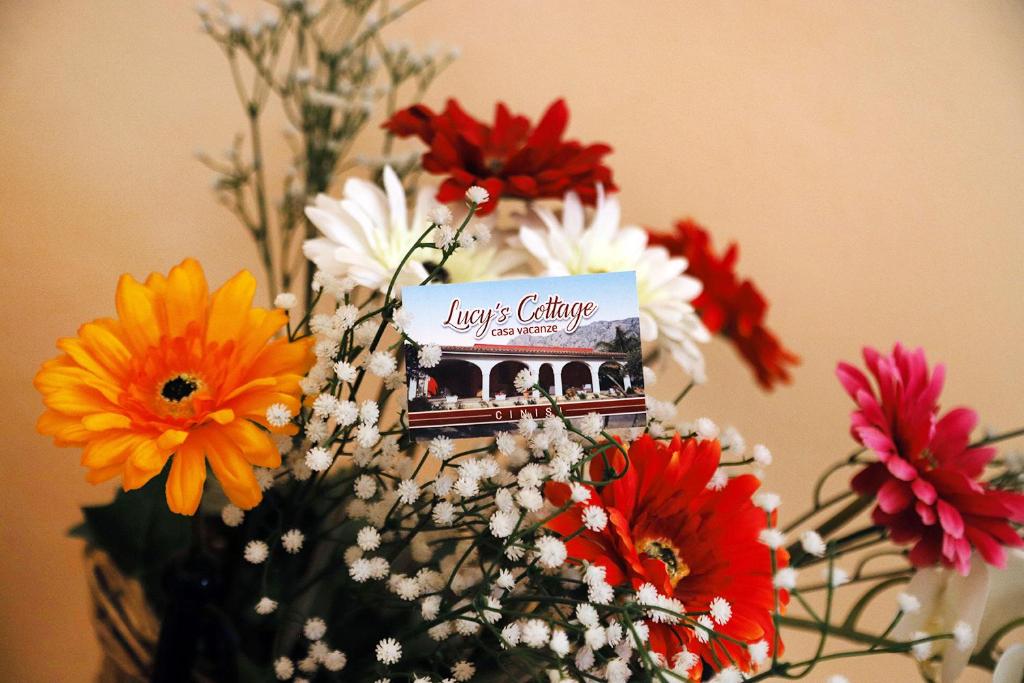 un vase rempli de fleurs avec un signe sur lui dans l'établissement Lucy's cottage, à Cinisi