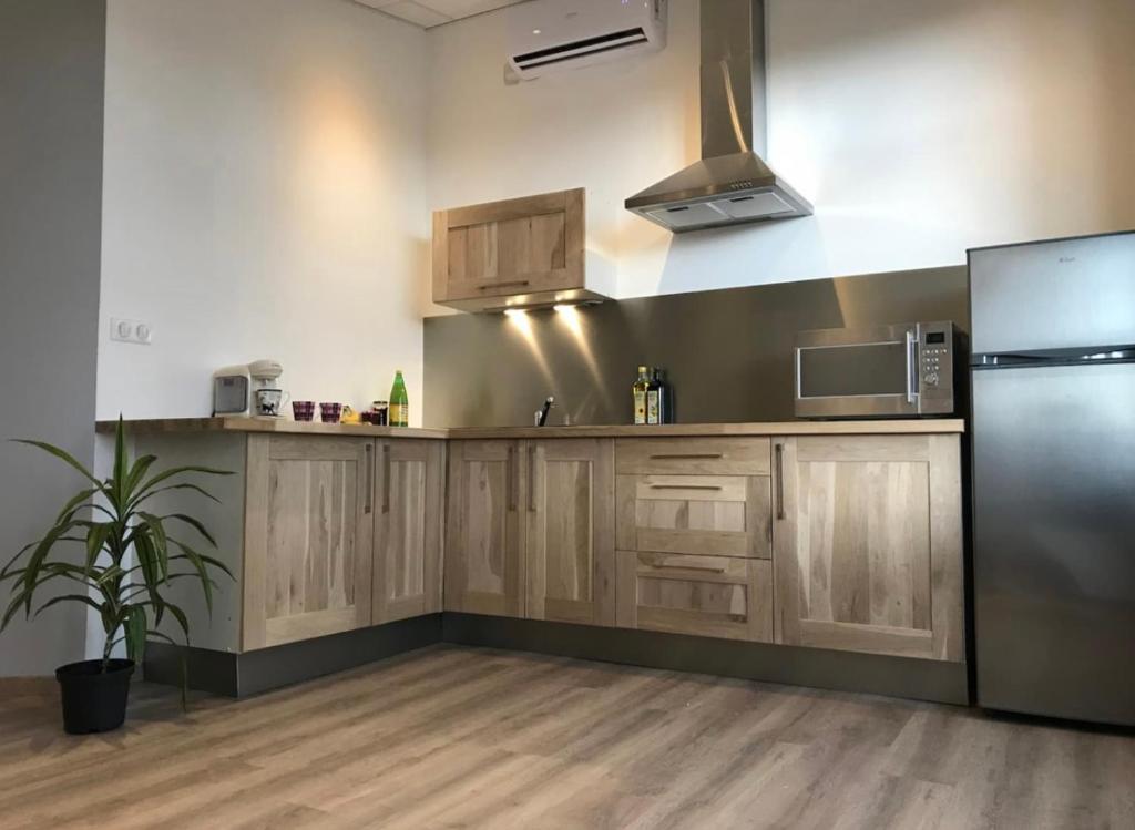 a kitchen with wooden cabinets and a stainless steel refrigerator at Résidence Harmonie Appartement N 4 meublé Avec Petit Déjeuner in Néris-les-Bains