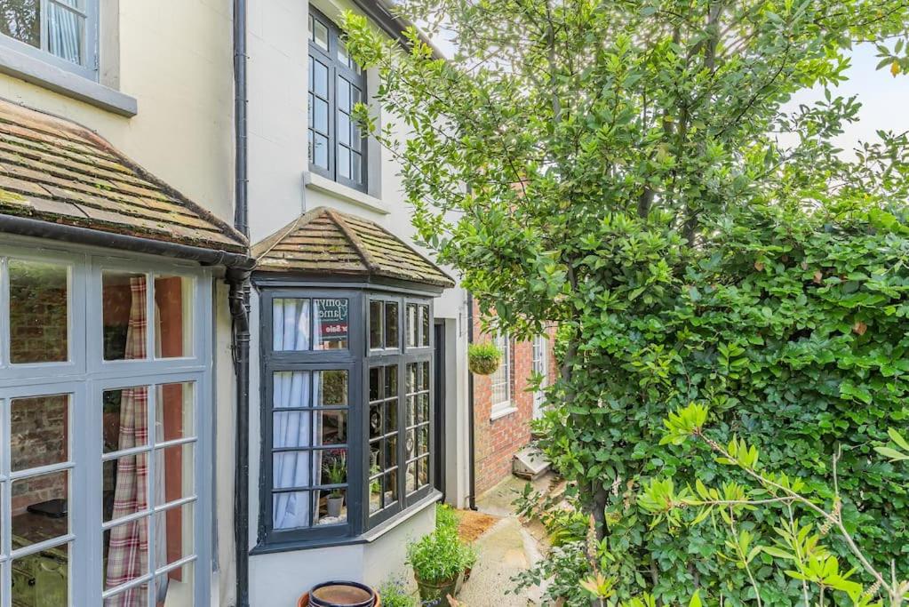 Elle offre une vue sur l'extérieur d'une maison dotée d'une fenêtre. dans l'établissement Pieman's Cottage - Pulborough, West Sussex Cottage - sunny courtyard, à Pulborough