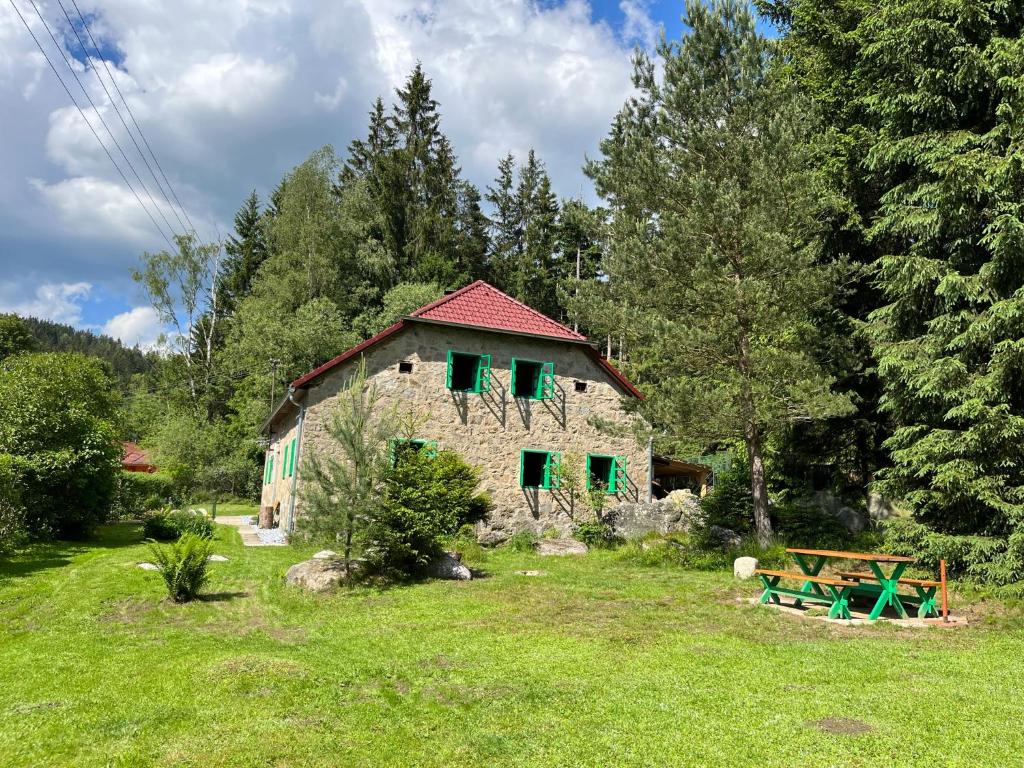 una casa de piedra con persianas verdes en un campo en Chalupa pod lipenskou hrází, en Loučovice