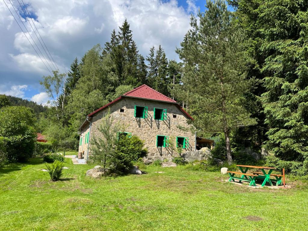 a stone house with green shutters in a field at Chalupa pod lipenskou hrází in Loučovice