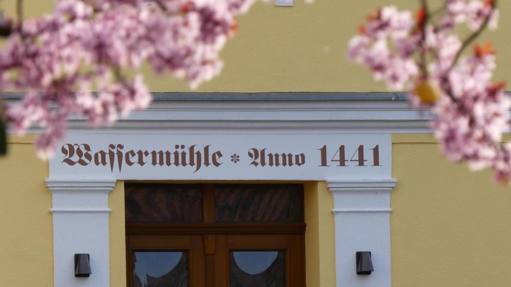 a building with a sign over a door with pink flowers at Pension Zur Mühle 