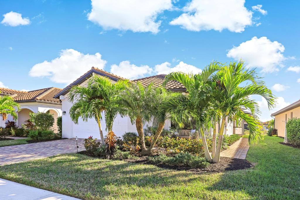 una casa con palmeras en un patio en Modern waterfront home in Artesia with pool/gym, en Lely Resort