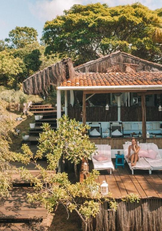 a woman sitting on a porch of a house at Eco-Casa Bobô in Ilha de Boipeba