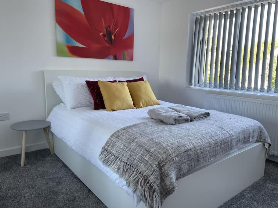 een witte slaapkamer met een bed met een rood bloemschilderij bij Paradigm House, Modern 2-Bedroom Duplex Apartment 2, Free Parking, Oxford in Oxford