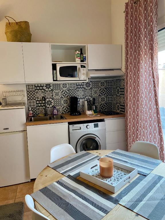 a small kitchen with a table and a microwave at 5 min du bord de mer in Hyères