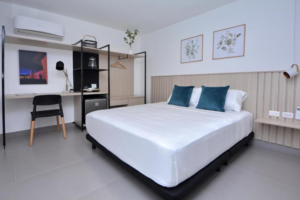 1 dormitorio con 1 cama blanca grande y escritorio en Reset (Hotel-Cafe-Coworking) en Cali