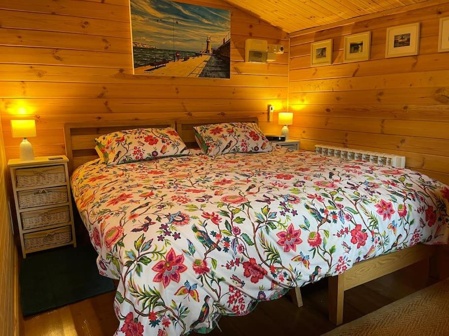 a bedroom with a bed in a wooden cabin at Cosy Cabin, hidden from the main house - Sleeps 2 - EV in Hawkinge