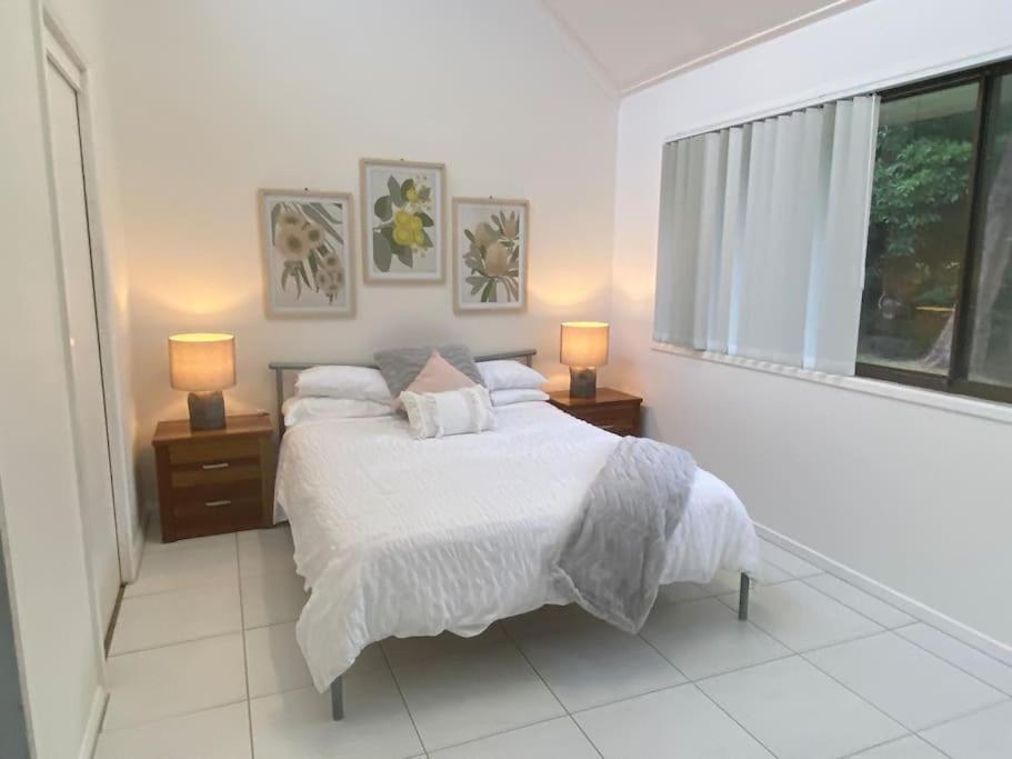 a white bedroom with a bed and two lamps at Bawley Point accommodation in Bawley Point