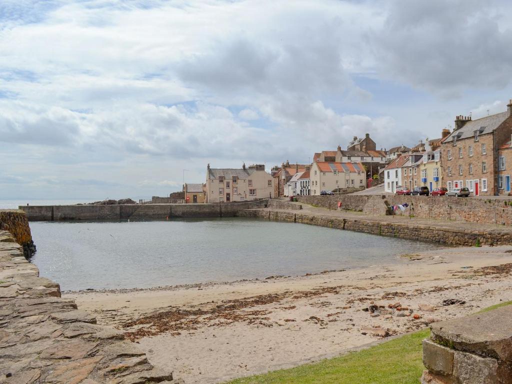 a body of water next to a beach with buildings at The Fishermans Loft in Cellardyke