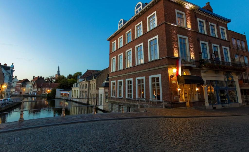 a building on a street next to a river at Canalview Hotel Ter Reien in Bruges