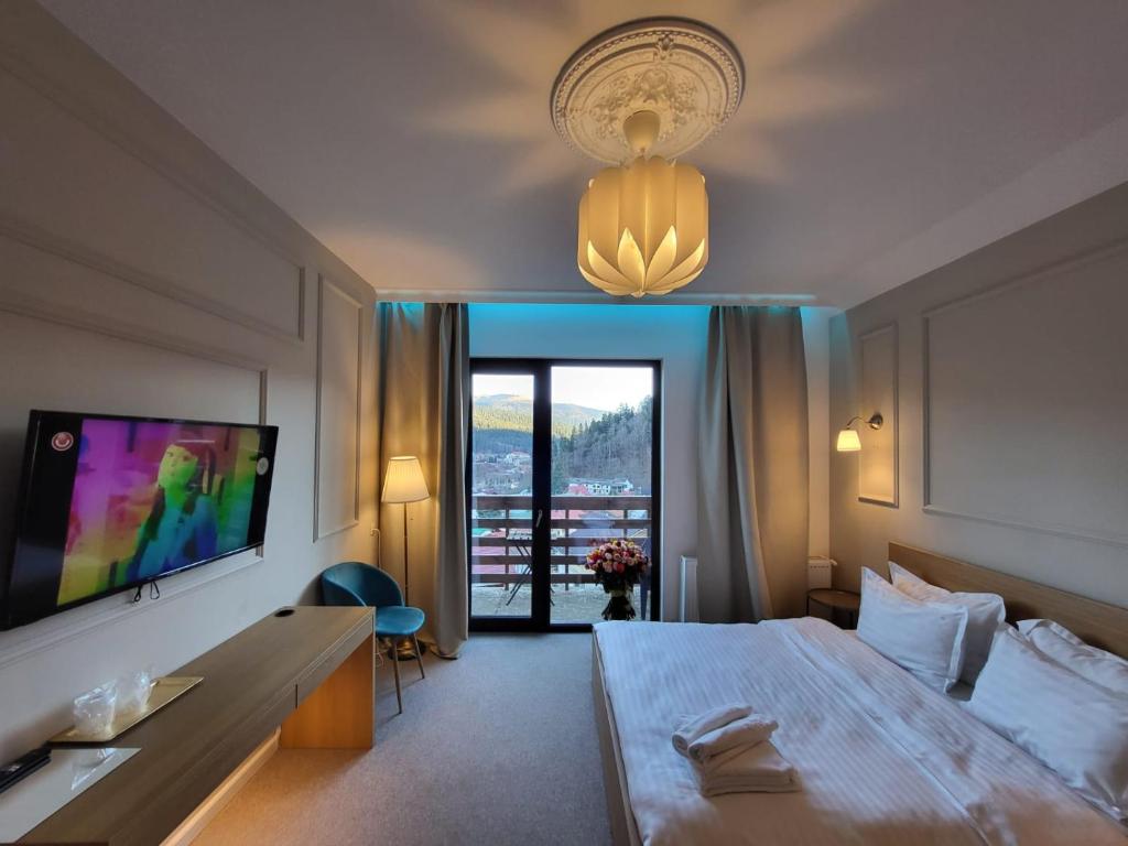 ブシュテニにあるVila PANORAMIC Busteniの大型ベッドとテレビが備わるホテルルームです。