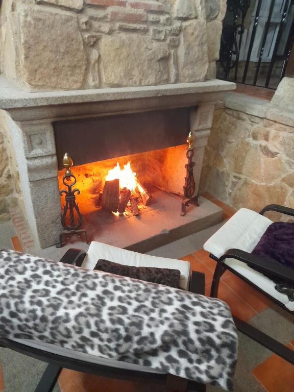 a stone fireplace with a table and chairs in front of it at Hotel Rural Sierra de Francia in Sotoserrano