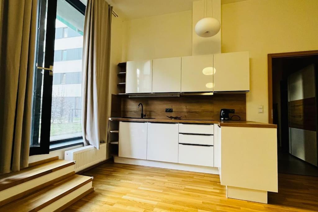 a kitchen with white cabinets and a large window at Apartment Holesovice, garden, garage in Prague