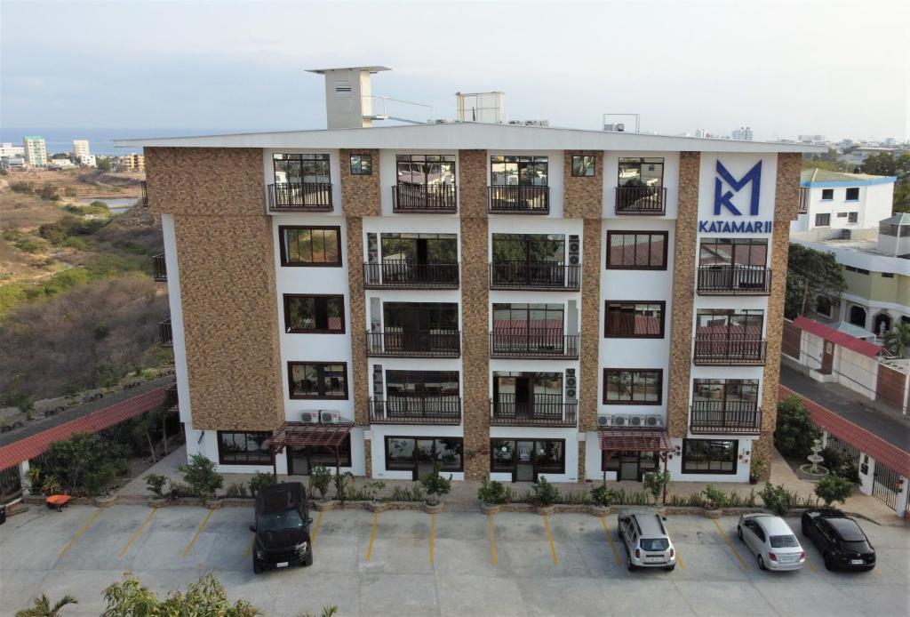un immeuble d'appartements avec des voitures garées dans un parking dans l'établissement Katamar, à Manta