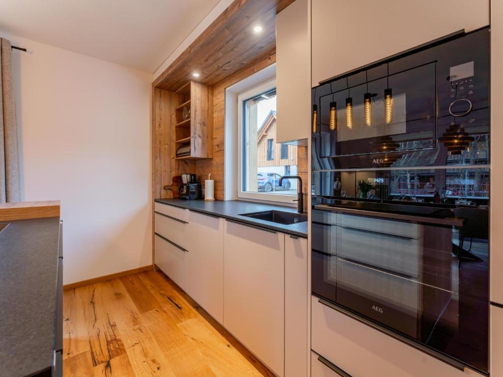 una cocina con armarios blancos y electrodomésticos negros en Mountain Chalet Alpinchique 2, en Sankt Lorenzen ob Murau