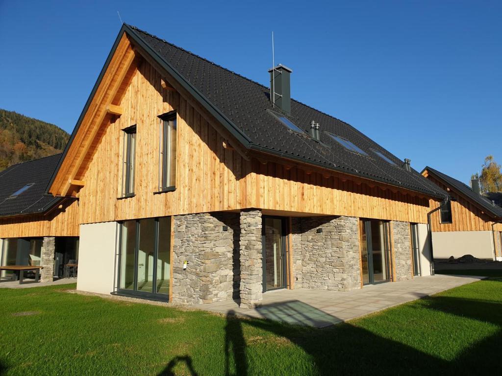 una casa con techo de madera y patio de césped en Mountain Chalet Krek Wak Wou en Sankt Lorenzen ob Murau