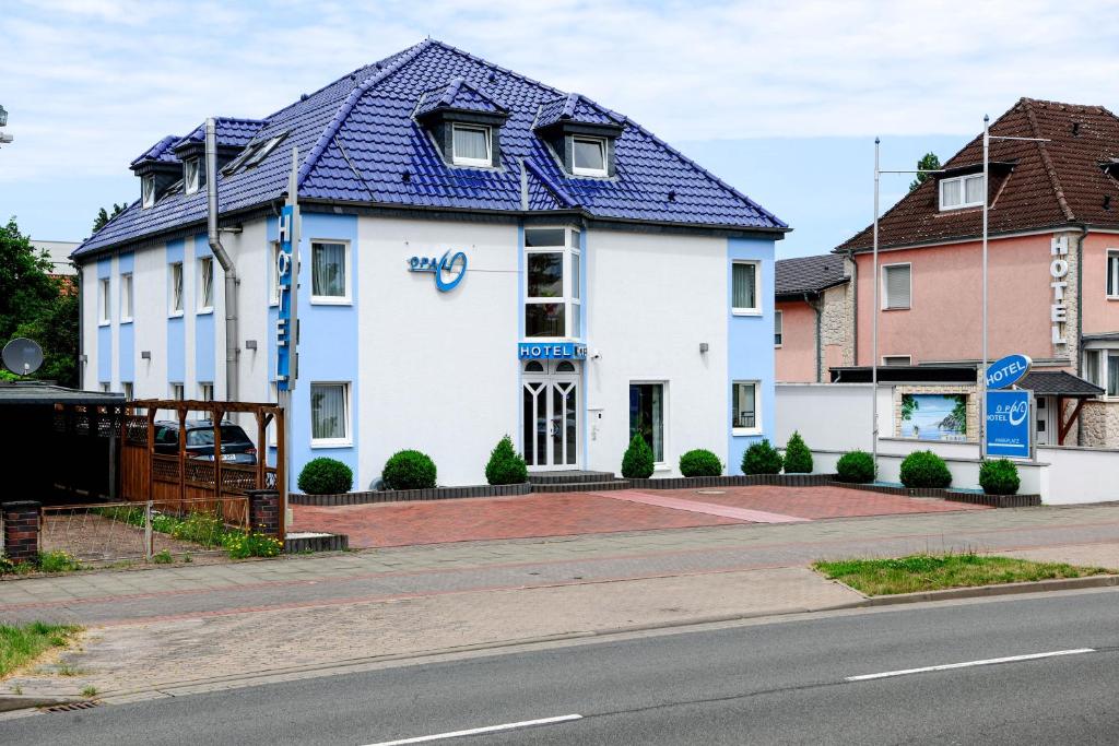 a white building with a blue roof on a street at Hotel Opal in Hannover