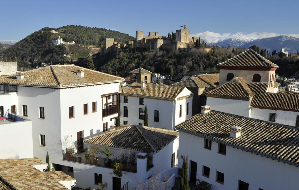 einen Blick auf die Dächer von Häusern mit einem Schloss im Hintergrund in der Unterkunft Smart Suites Albaicin in Granada