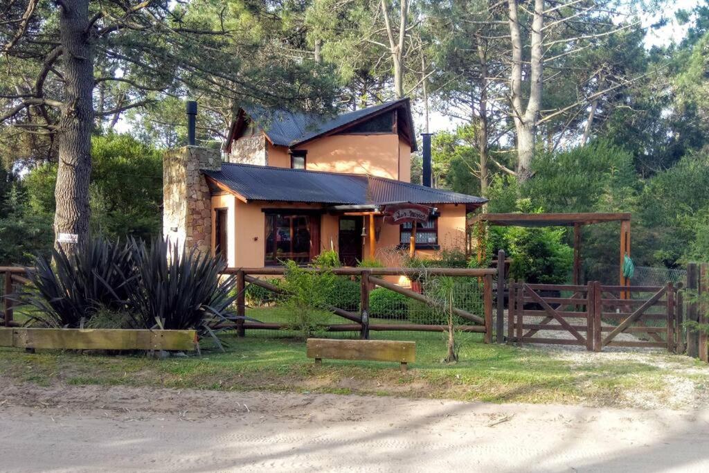 una pequeña casa con una valla delante de ella en Las Nenas. Un paraíso en el bosque en Balneario Mar Azul