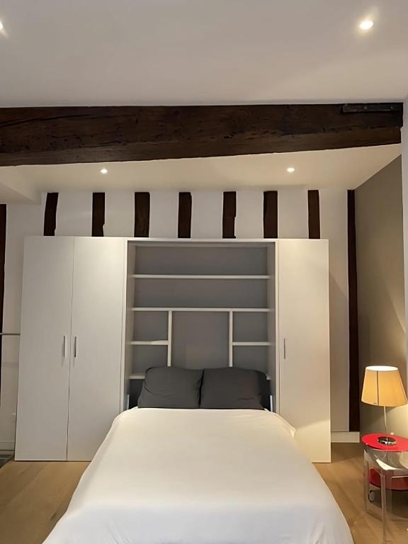 - une chambre avec un grand lit blanc et une tête de lit dans l'établissement Modern Apartment in the Heart of St-Germain, à Paris