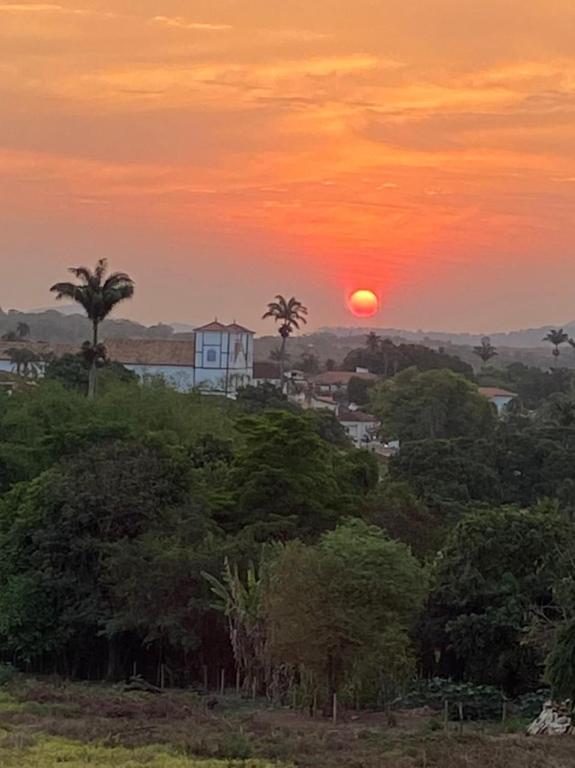 a sunset with a house on a hill with trees at Resort Quinta Santa Barbara 30 dez 2025 a 06 jan 2026 in Pirenópolis