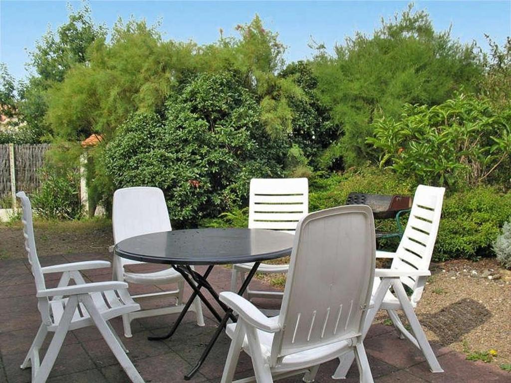 4 chaises blanches, une table, une table et des chaises dans l'établissement Maison proche plage, au calme, Wi-Fi, jardin, animaux acceptés - FR-1-22-318, à La Tranche-sur-Mer
