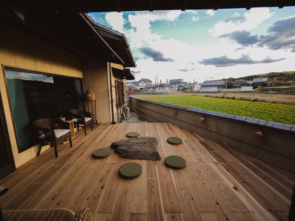una terraza de madera con 4 piedras verdes. en 古民家ゲストハウス CHACHACHA AWAJI, en Awaji