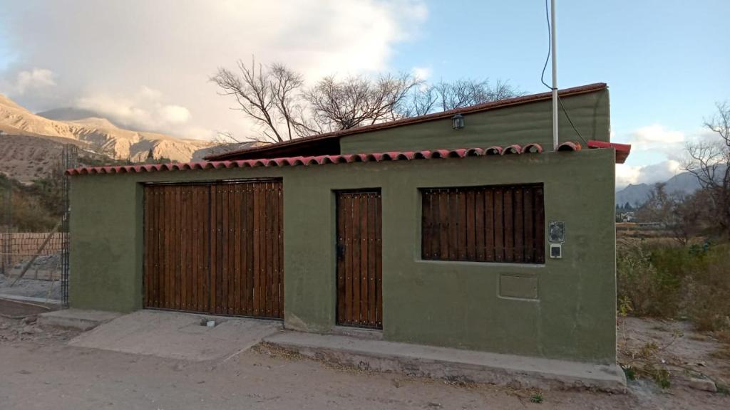 un pequeño edificio verde con dos puertas y una valla en Cabaña La Soñada en Tilcara